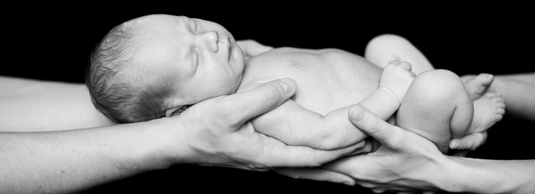 Newborn baby sleeps in a father's hands